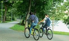two girls cycling through the park together