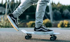 person's feet while skatboarding with one foot on board and one foot propelling